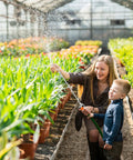 Woman and child using 29 Inch Stainless Steel Sprayer Wand With Adjustable Nozzle And Built In Shut Off Valve in greenhouse