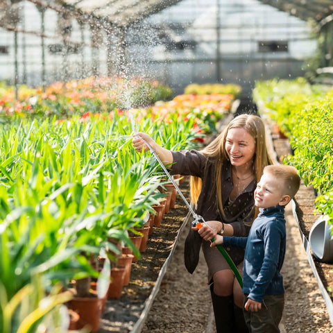 Woman and child using 29 Inch Stainless Steel Sprayer Wand With Adjustable Nozzle And Built In Shut Off Valve in greenhouse