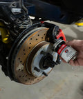Applying Premium 4oz Brush Top SIL Glyde Silicone Brake Grease for Calipers and Brake Lubrication to car brake caliper