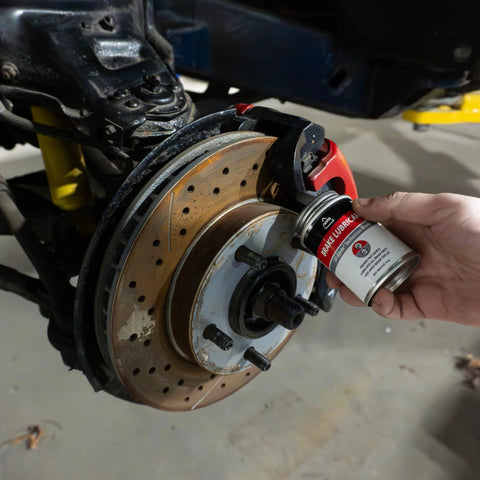 Applying Premium 4oz Brush Top SIL Glyde Silicone Brake Grease for Calipers and Brake Lubrication to car brake caliper