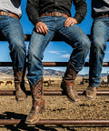 Three cowboys sitting on a fence, wearing jeans with Two Piece Leather Spur Straps For Cowboy Boots, Adjustable Western Boot Straps