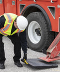 Worker placing HDPE Outrigger Pad 18x18x1 Inch Heavy Duty Jack Pad For Utility Trucks Cranes RVs Trailers Campers on asphalt