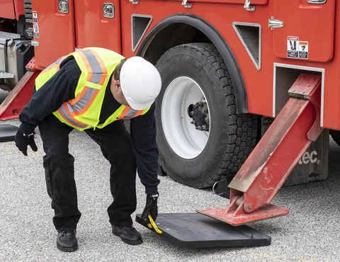 Worker placing HDPE Outrigger Pad 18x18x1 Inch Heavy Duty Jack Pad For Utility Trucks Cranes RVs Trailers Campers on asphalt