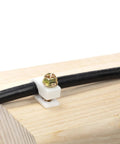 Ribbed Plastic Conical Wall Anchors And Cable Clips Set installed on wood with black cable secured by white clip.