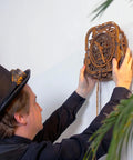 Person installing Gear Globe Wall Clock Kit With 369 Laser Cut Pieces, DIY Wooden 3D Puzzle Clock on wall, mechanical globe design