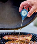 ThermoPop 2 Instant Read Thermometer In Cayenne Red For Quick Accurate Food Temperature Checks held over grilling steak