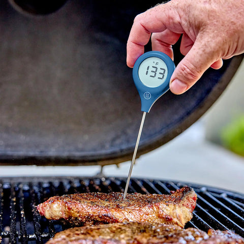ThermoPop 2 Instant Read Thermometer In Cayenne Red For Quick Accurate Food Temperature Checks held over grilling steak