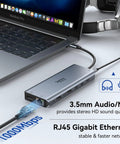 Triple Monitor USB C Docking Station 13-In-1 Hub With Dual HDMI And DisplayPort connected to laptop showing Ethernet cable and audio/mic port