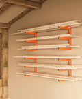 Beefy Heavy Duty Wood Organizer And Lumber Storage Wall Mount Rack With Six Levels Holds Up To 1200 Lbs Indoors Or Outdoors In Bright Orange installed on a wall with wooden beams and lumber