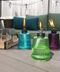 Carnival Glass Tabletop Torches 3 Pack for Patio Backyard and Garden Lighting in blue, green, and purple on outdoor table