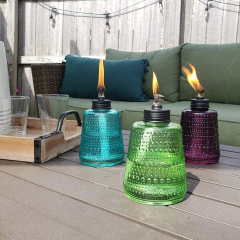 Carnival Glass Tabletop Torches 3 Pack for Patio Backyard and Garden Lighting in blue, green, and purple on outdoor table