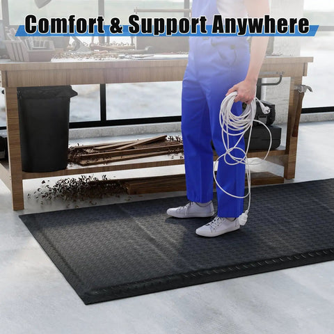 Person standing on a 3 By 7 Foot Anti Fatigue Floor Mat Extra Thick One Inch For Machinist Shop Garage Standing Pad with black anti-static rubber top in workshop.