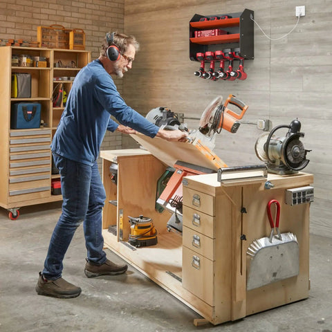 Man using saw in workshop with Heavy Duty Wall Mount Drill Organizer and Cordless Tool Storage Rack visible on wall