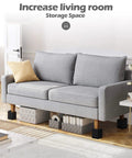 Give Your Bed Or Sofa A Legit Boost With These Heavy Duty Furniture Risers Featuring Adjustable Heights Anti Slip Grip Shock Absorbing Base And Rock Solid Support Handling Up To 1300 Lb Load In Sleek Black under a grey couch with storage bins.