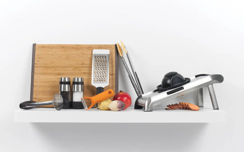 Kitchen tools with Stainless Steel Salt And Pepper Grinder Set for kitchen and table, cutting board, slicer, and vegetables on a shelf.