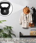 Dead Reliable Cast Iron Fish Wall Hooks 2 Pack display with a 35-pound kettlebell, holding coats and bags in an entryway.