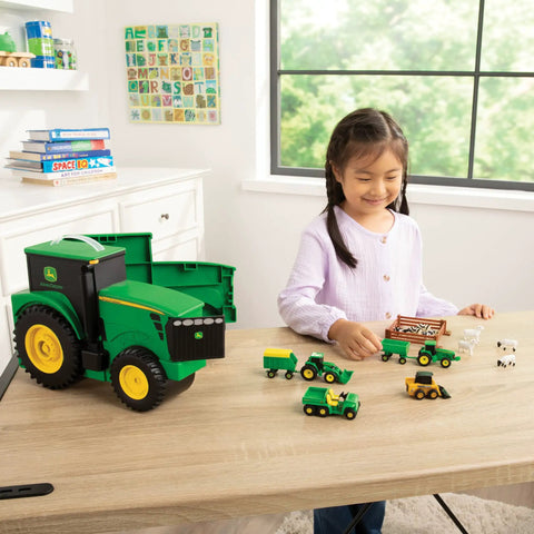 Child playing with John Deere Tractor Toys Value Set With Portable Carrying Case, featuring die-cast vehicles on a table setup.
