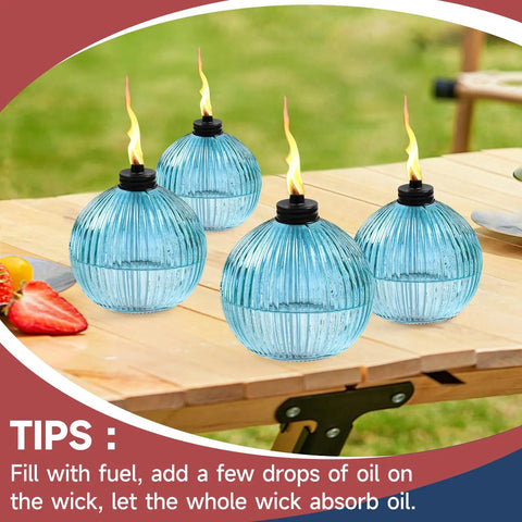Citronella Torch Set Of Four 16 Oz Blue Glass Outdoor Garden Torches With 3 Prong Ground Stake 58.6 Inch Tall on a table