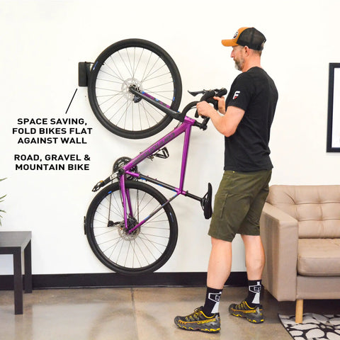 Man adjusting Velo Hinge Two Point Zero Pivoting Bike Wall Mount Single Vertical Bicycle Hanger in garage with folded bike