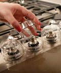 Stove And Oven Knob Safety Cover Set L730A Five Count Pack Easy To Install Kid Safe Kitchen Accessory Clear in use on stove.