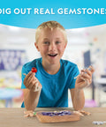 Child using Gemstone Dig Kit For Kids With 15 Real Gemstones And Crystals Hands On Science Toy For Boys And Girls. Classroom setting.