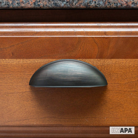 Oil Rubbed Bronze Cabinet Cup Pulls Three And A Half Inch Overall Length 10 Pack Durable Drawer Handles installed on wooden cabinet.