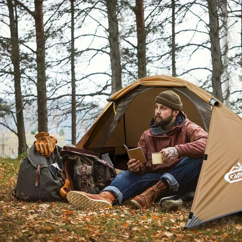 Man sitting in Lightweight 1 Person Tent For All Seasons, Windproof, Rainproof And Waterproof Camping Tent For Hiking, reading with gear.
