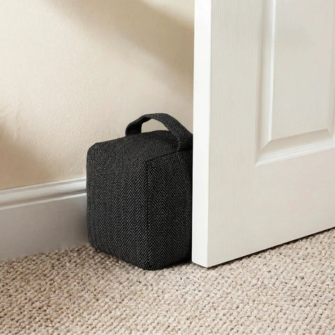Heavy Duty Weighted Door Stopper With 4.4 Lb Internal Weight keeps door stable, resting against a white door on carpeted floor.