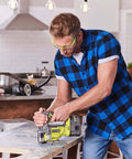 Man using Ryobi smooth cordless jigsaw on wooden surface in modern kitchen, part of Top Notch 18 Volt Power Tool Combo Kit.