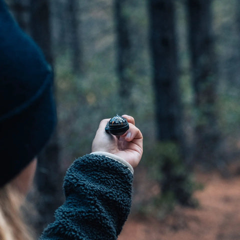 Person holding Ball Compass And Thermometer Carabiner For Hiking And Camping Clip On Grab And Go Gear in a forest setting