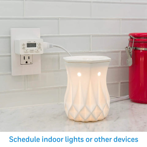 24 Hour Digital Plug Timer With One Polarized Outlet No Fuss Two Programmable On Off Cycles For Lamps And Indoor Lighting 125VAC Indoor Timer White 1 Pack Model 45184 plugged in next to a decorative lamp on a countertop.