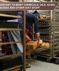 User handling fresh bread on a metal rack with Built Like A Tank High Temp Caster Wheels For Bakery Ovens 570F Heat Resistant Glass Filled Nylon Swivel Rollers Handling Two Thousand Eight Hundred Pound Loads Daily.