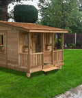 Wooden garden shed with porch and windows on a lawn under a cloudy sky.