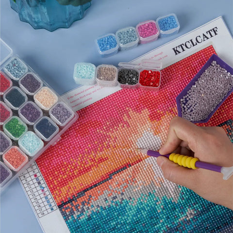 Crafting hand using pen on diamond art canvas with beads, part of 46 Piece DIY Diamond Painting Tools And Accessories Kit.