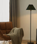 Must Have Black Pole Floor Lamp With Adjustable Height And Dark Green Shade, Metal Base, LED Bulb Included, stands by armchair.