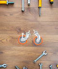 4pcs Inch M8 TPR Rolling Furniture Casters with Brake Orange displayed on a wooden surface surrounded by tools.