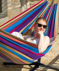 Person relaxing in Outdoor Double Hammock Portable With Colorful Stripes Cocoon Style Comfort For Camping And Backyard Chill Vibe