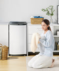 Woman kneeling in front of a Top Shelf Portable Washer For Tiny Apartments And Studios White with a soft towel.