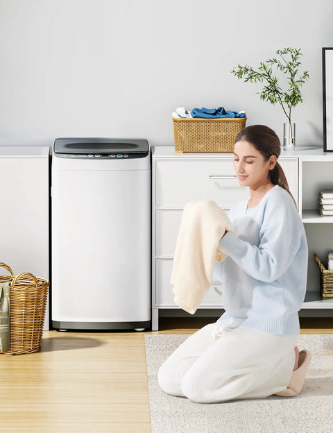 Woman kneeling in front of a Top Shelf Portable Washer For Tiny Apartments And Studios White with a soft towel.