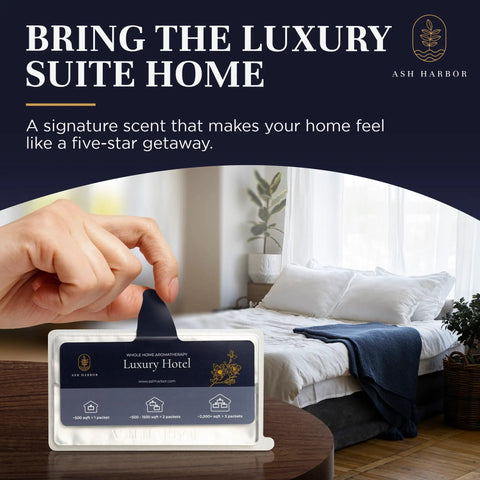 Hand holding Luxury Hotel Scent Whole Home Air Freshener System package in bedroom setting with spa-like decor.