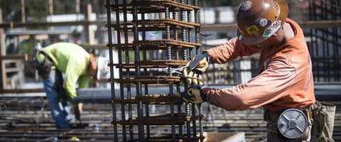 Construction worker wearing Material4X M Pact Work Gloves With Impact Guard And D3O Palm Padding handling rebar on site.