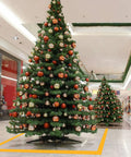 Decorated Christmas trees in a shopping mall with yellow floor marking tape forming a safety boundary.