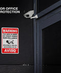 The Real Deal 24 Hour Security Camera Alert Eight By Twelve Inch Reflective Aluminum Yard Sign on office door, bilingual warning.