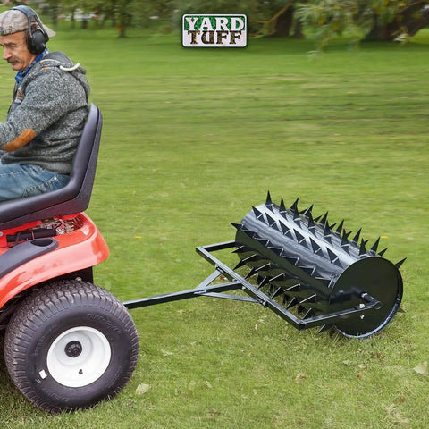 Man using 36 Inch Wide Lawn Aerator Roller With 78 Steel Spikes And 24 Gallon Water Holder for deep lawn aeration behind ATV on grass