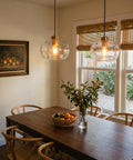 CASAMOTION Glass Pendant Lights, Textured Clear Globe Shade illuminating a rustic dining table with natural decor.