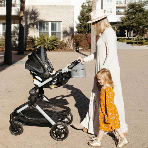 Keep It Chill On The Fly Breastmilk Bottle Cooler Travel Bag With Included Freezing Insert attached to stroller on a sunny day.