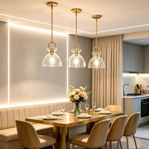 Super Sleek Brushed Gold Pendant Light For Kitchen Island Featuring Fully Adjustable Hanging Cord And Large Clear Glass Shade above modern dining table.