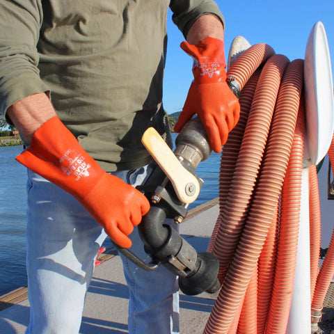 Person wearing Atlas 620 Double-Dipped PVC Chemical Resistant Gloves with Rough Grip handling industrial hose outdoors.