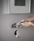 Person using Corded 120V 5 Amp Multi Max Oscillating Tool Kit With Accessories for precise cuts in wall, low vibration control