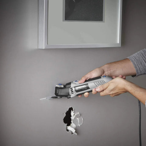 Person using Corded 120V 5 Amp Multi Max Oscillating Tool Kit With Accessories for precise cuts in wall, low vibration control
